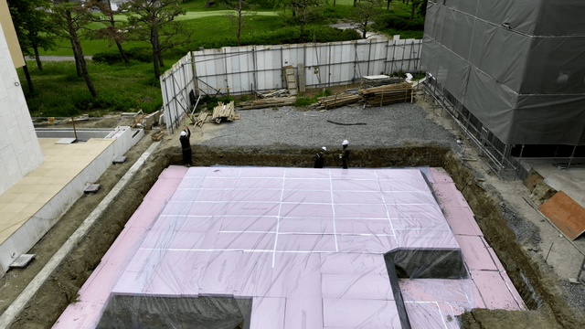 Workers laying insulation at a construction site