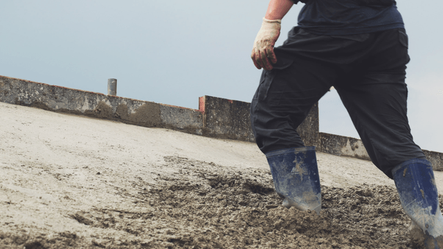 Worker smoothing wet concrete on a slope