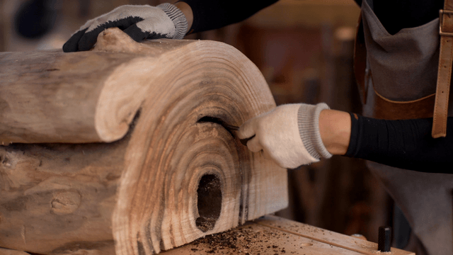 Artisan carving grooves into a wooden barrel with an awl