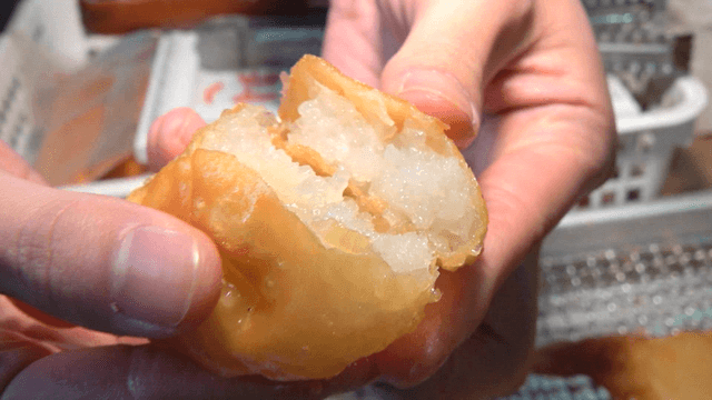 Hand opening a steaming fried dumpling
