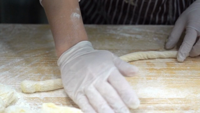 Hands shaping dough on a floured surface