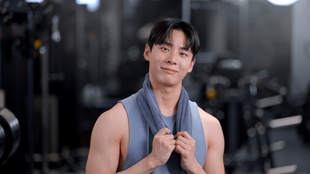 Young man facing forward with a towel around his neck at gym