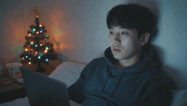 크리스마스 트리가 있는 어두운 방에서 노트북을 사용하는 젊은 남성