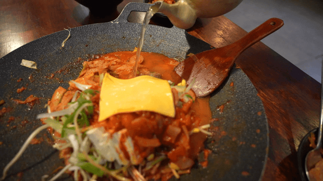 Kettle pouring broth into budaejjigae