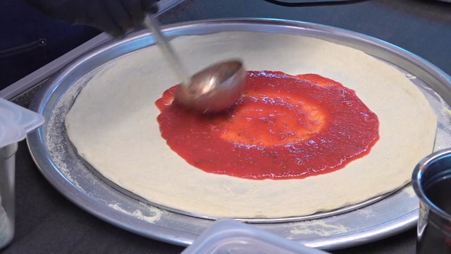 Spreading tomato sauce on pizza dough