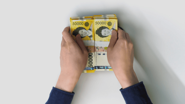 Hand placing Korean banknotes on a tray"