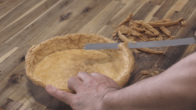 나무 테이블 위에서 파이 크러스트를 다듬는 제빵칼