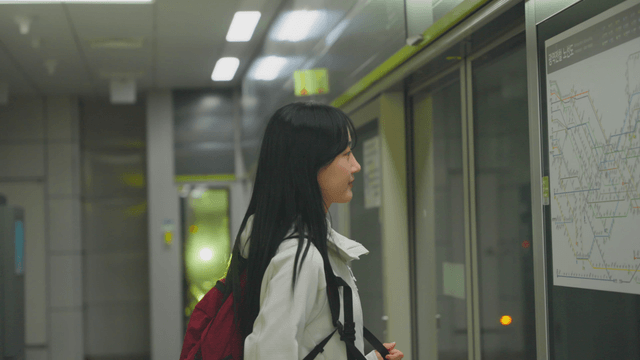 Young woman checking subway line in front of screen doors