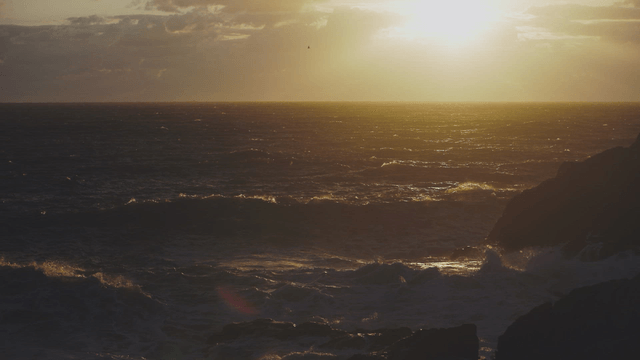 Sunset over the ocean with waves crashing