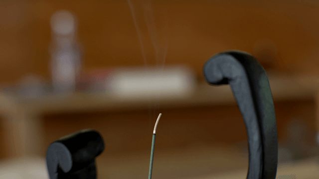 Incense smoke rising among wooden sculptures