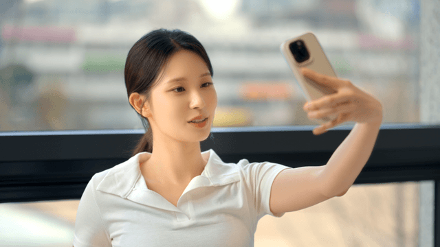 Young woman taking a selfie by the window