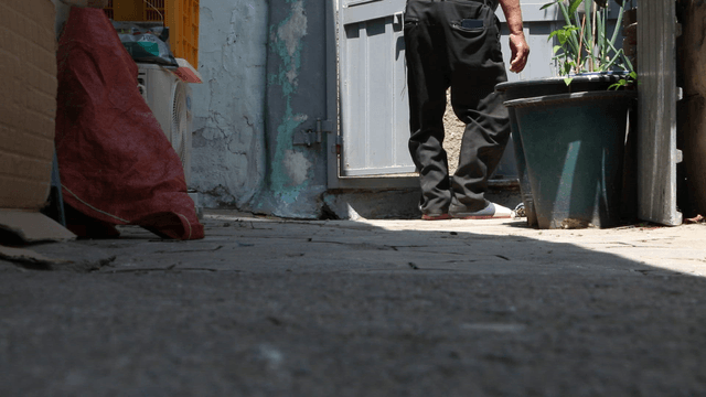 Elderly person opening the front door in a small yard