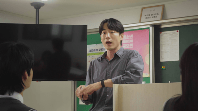 Teacher interacting with students while standing near the desk