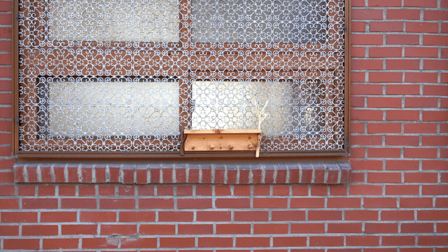 Wooden shelf attached to a decorative window of a brick house