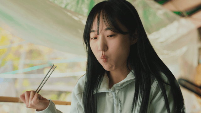 Young woman enjoying meal with chopsticks in forest lodge