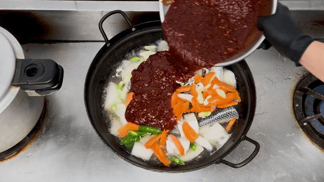 Spicy mackerel and radish stew with sauce added to boiling pot