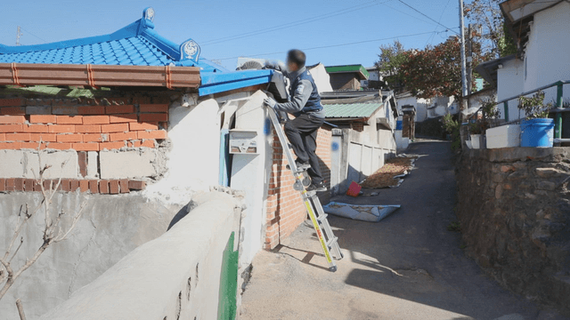 작은 골목에서 지붕 작업 중인 남성