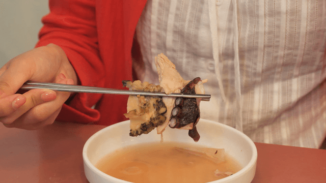 Chopsticks holding abalone, chicken, and octopus from chicken and seafood soup