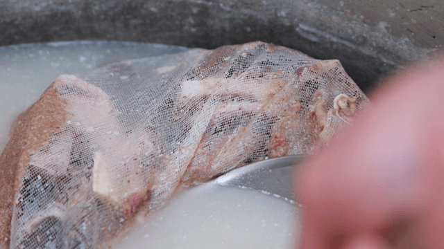 Beef bones in milky broth strainer inside pot