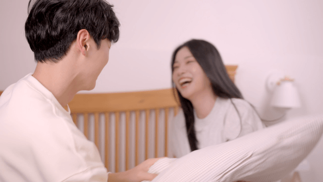 Playful couple having a pillow fight on bed