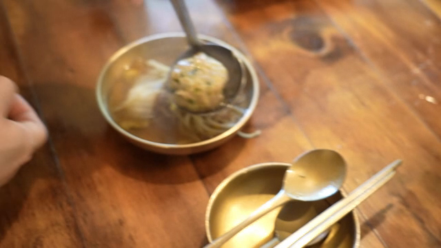 A person scooping dumplings out of hot pot