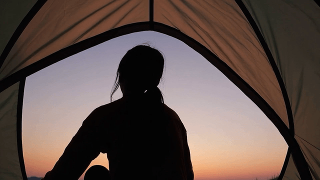 Silhouette of a person in a tent at sunrise