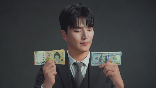 Man smiling at the Korean won in his hand