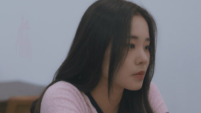 Side view of a serious woman wearing a pink knit top