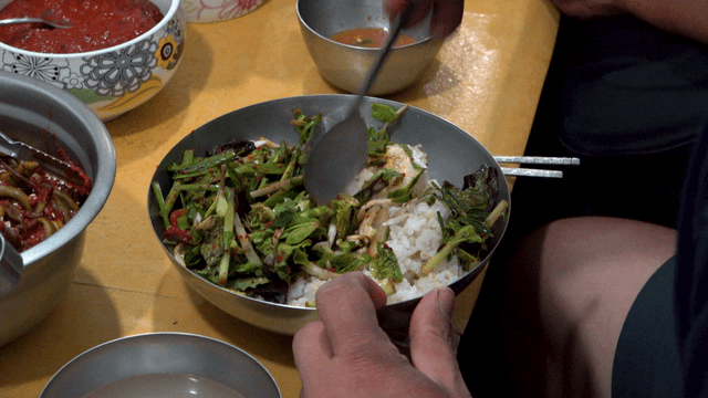 Mixing barley rice with assorted vegetables in stainless bowl