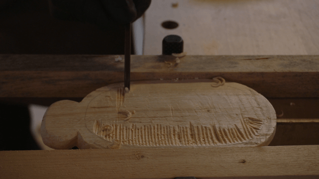 Hands delicately carving wood with a chisel in workshop