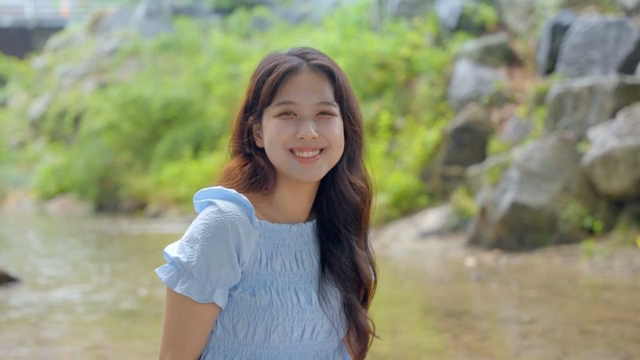 고요한 시냇가에서 미소 짓는 여성