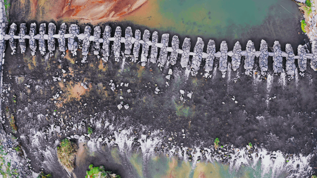 Aerial view of a stone bridge across a clear river