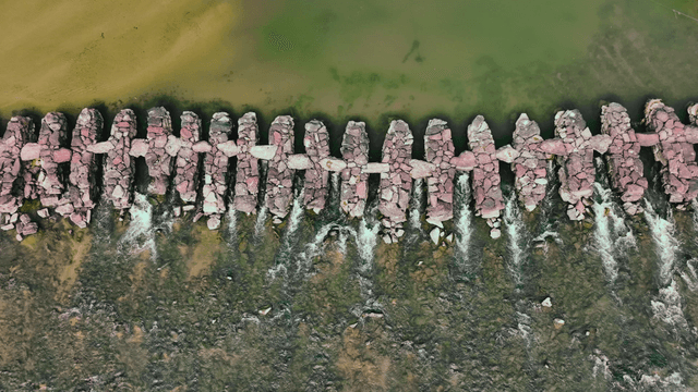 Aerial view of a stone bridge along the green river