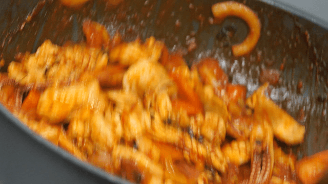 Ladle stir-frying vegetables and seafood in a pan