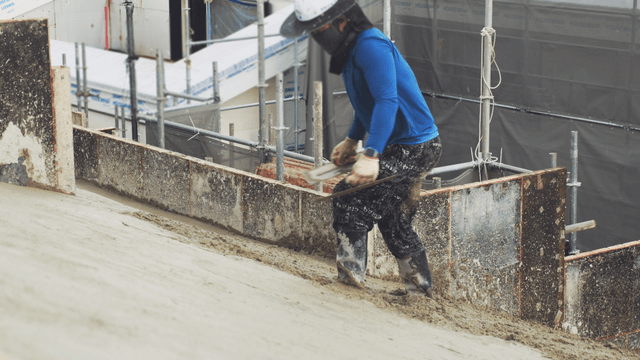 Worker smoothing concrete on a slope