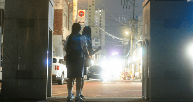 Two students standing on a city street at night