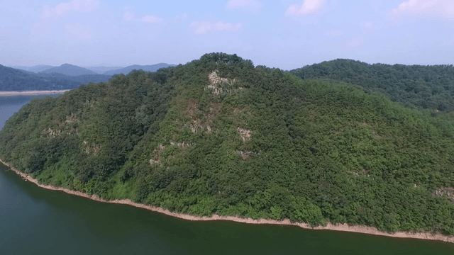 Green mountain beside a calm river