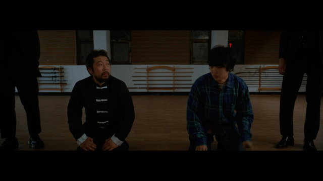 Two people kneeling in a martial arts dojo