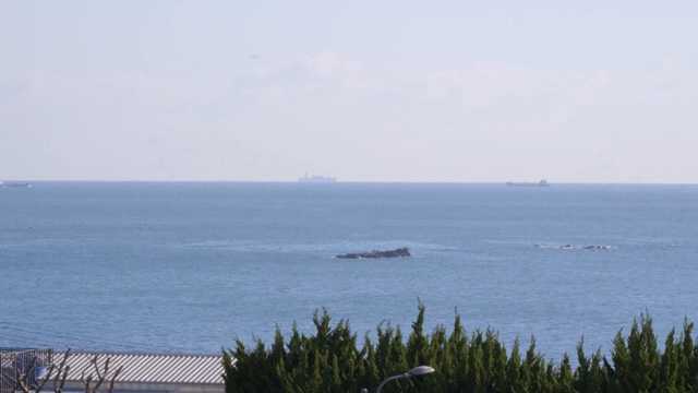Calm sea with distant ships and rocks