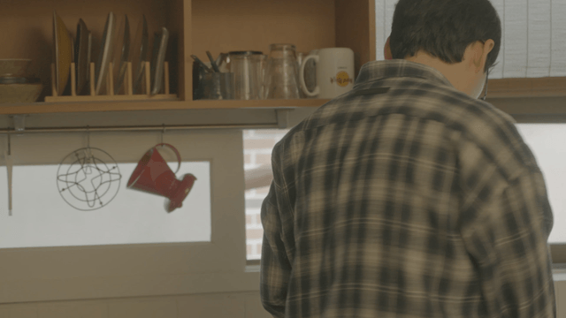 Man in a kitchen with shelves and cups
