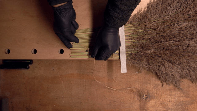 Hands crafting a broom with natural materials