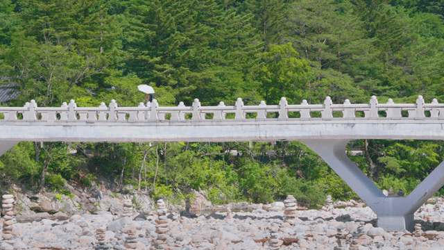 Person with parasol crossing stone bridge
