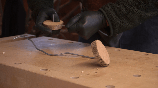 Craftsman embedding metal wire into wooden block