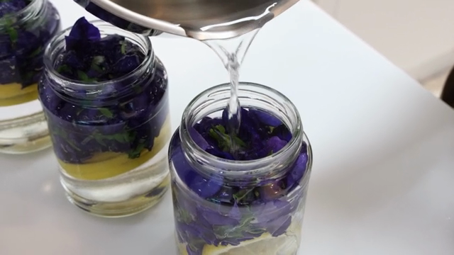 Pouring liquid into jars with flowers