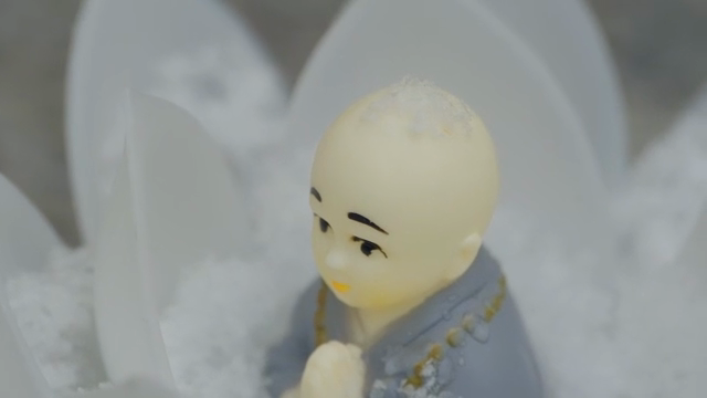 눈에 둘러싸인 작은 승려 조각상