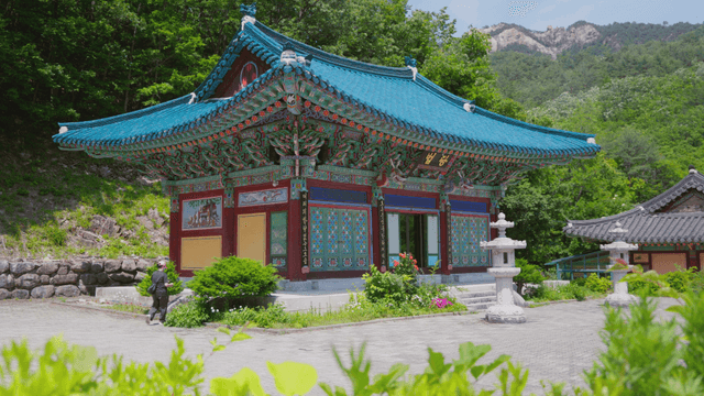 산을 배경으로 한 전통 한국 절과 입장하는 여성
