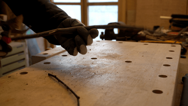 Person trimming branches with pruning shears at workbench