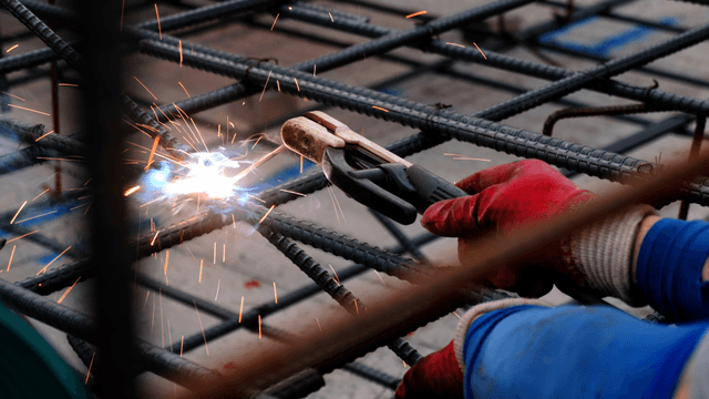 Worker welding steel bars at a construction site