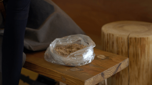 Woodcraft artisan transferring sawdust into a plastic bag by hand