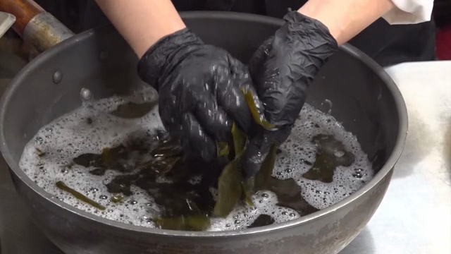 Hands preparing kelp in a pot